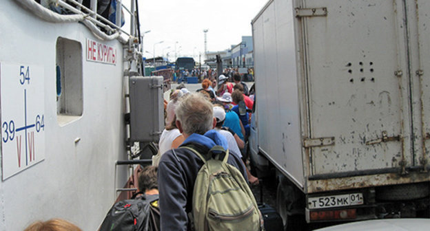 Manoeuvring of the flow of people between small-tonnage vehicles during disembarkation form the ferry. Port "Caucasus", August 2014. Photo by Nina Tumanova for the "Caucasian Knot" Manoeuvring of the flow of people between small-tonnage vehicles during disembarkation form the ferry. Port "Caucasus", August 2014. Photo by Nina Tumanova for the "Caucasian Knot"