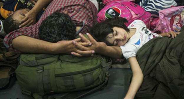 An exhausted Syrian girl is asleep next her father after they have been saved by the Italian ship. Photo: @UNHCR/A.D’Amato, http://www.unhcr.ru/