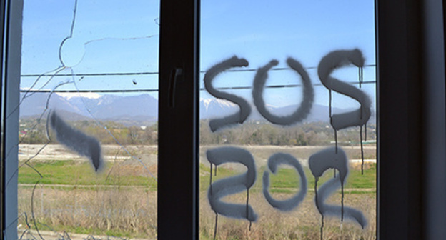 Inscription 'SOS' on the window of dilapidated house of cottage settlement for Olympic resettlers, Vesyoloe-Psou neighbourhood, Adler District of Sochi. Photo by Svetlana Kravchenko for the ‘Caucasian Knot’.