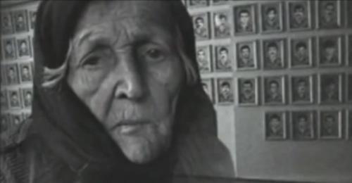 An elderly woman near the photos of the victims of war and deportation. Photo: screenshot of the video on the YouTube channel vainakh38 An elderly woman near the photos of the victims of war and deportation. Photo: screenshot of the video on the YouTube channel vainakh38