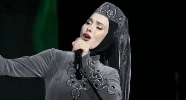 Aina Getagazova signing at the concert in Grozny. Screenshot from Youtube video posted by Chechnya.095: https://www.youtube.com/watch?v=nzOASGDmYYE Aina Getagazova signing at the concert in Grozny. Screenshot from Youtube video posted by Chechnya.095: https://www.youtube.com/watch?v=nzOASGDmYYE