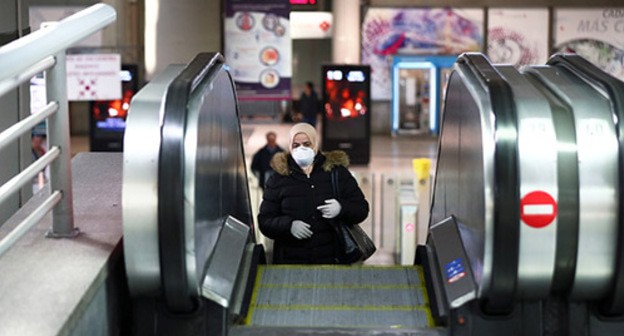A woman in a medical mask riding an escalator. Photo: REUTERS/Sergio Perez A woman in a medical mask riding an escalator. Photo: REUTERS/Sergio Perez