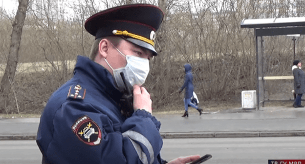 Policeman with smartphone in his hands. Screenshot: https://www.youtube.com/watch?v=NPQgNeW1dGI Policeman with smartphone in his hands. Screenshot: https://www.youtube.com/watch?v=NPQgNeW1dGI