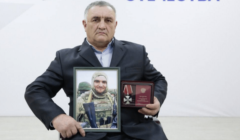 Ramazan Aripshev's father with his son's portrait and award. Screenshot of a photo from the Telegram channel of the Defenders of the Fatherland Foundation in Kabardino-Balkaria from 04.08.25, https://t.me/fond_ZO_kbr/7081.