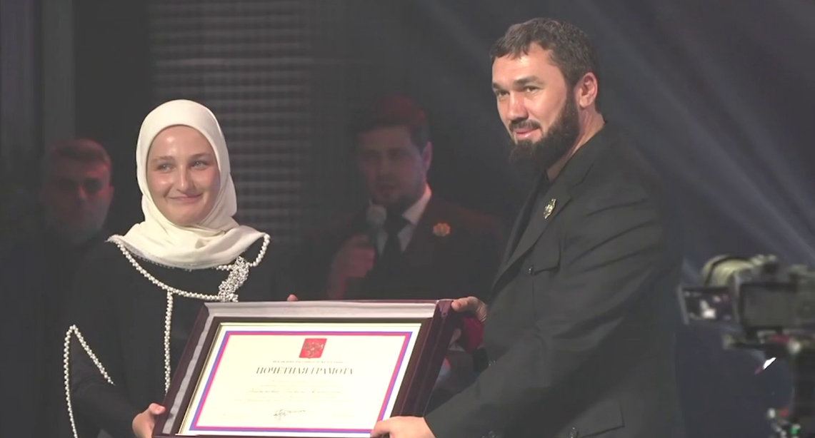 Magomed Daudov (right) presented a certificate to Khadizhat Kadyrova. Still from a video from Ramzan Kadyrov's Telegram channel, October 8, 2025, https://t.me/RKadyrov_95/6071.

