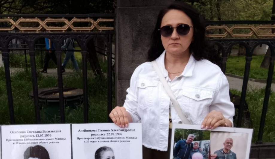 A picketer holds signs. Screenshot from RusNews photo from May 2, 2026, https://t.me/rusnews/84132.