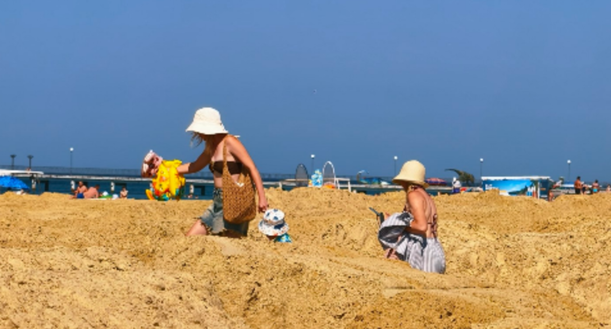 Tourists are making their way among the piles of sand to the beach in Vityazevo. Screenshot photo by Andrey Makovozov from 19.07.26, https://t.me/makovozovy/64553 Tourists are making their way among the piles of sand to the beach in Vityazevo. Screenshot photo by Andrey Makovozov from 19.07.26, https://t.me/makovozovy/64553
